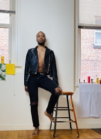 a man in a leather jacket posing in front of a window